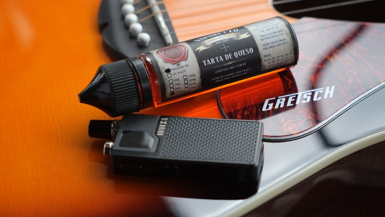 Close-up shot of a vape liquid and device on a Gretsch guitar, blending music and modern technology.