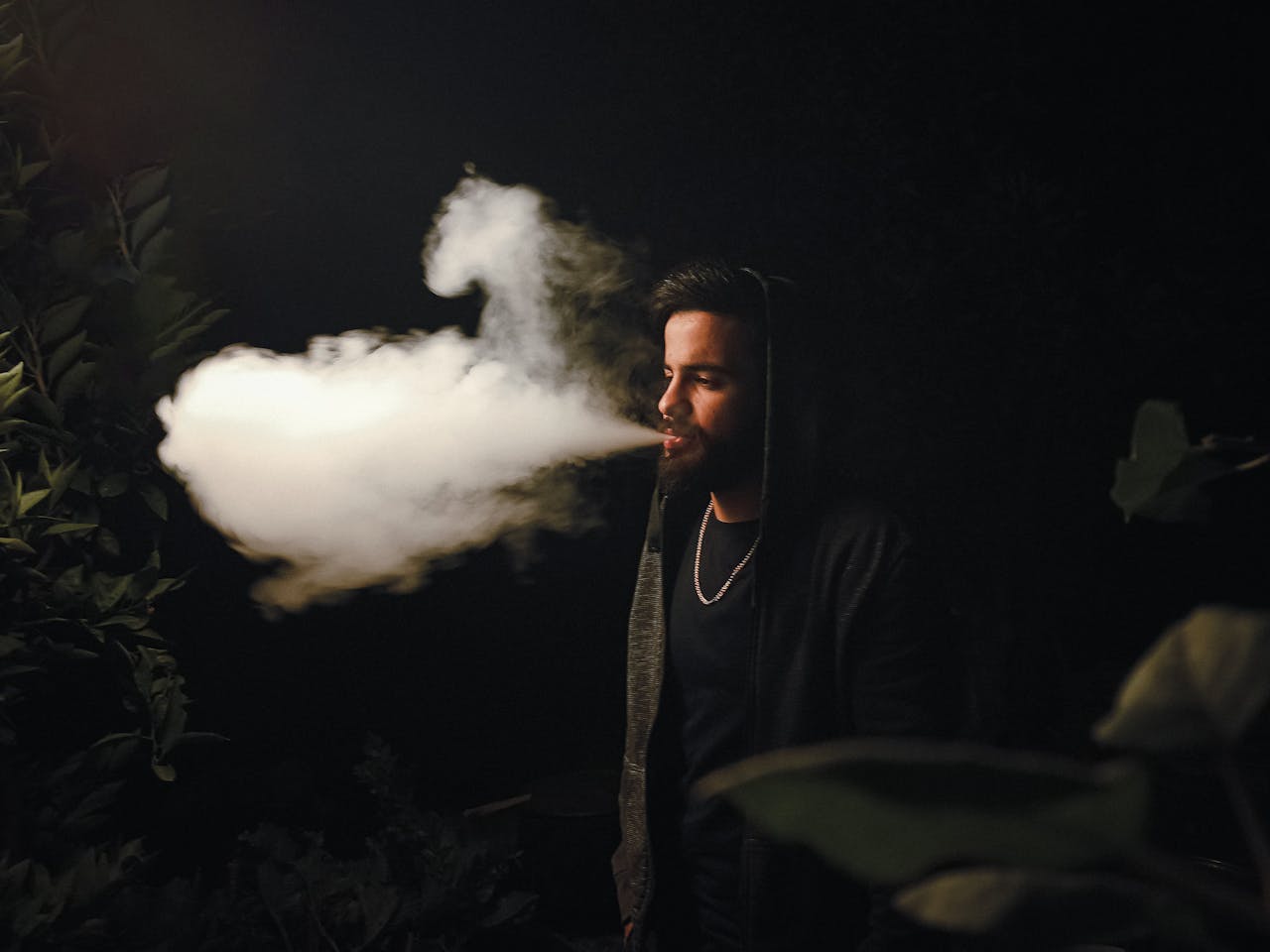 Portrait of a man exhaling thick vapor at night outdoors in Fethiye, Türkiye.