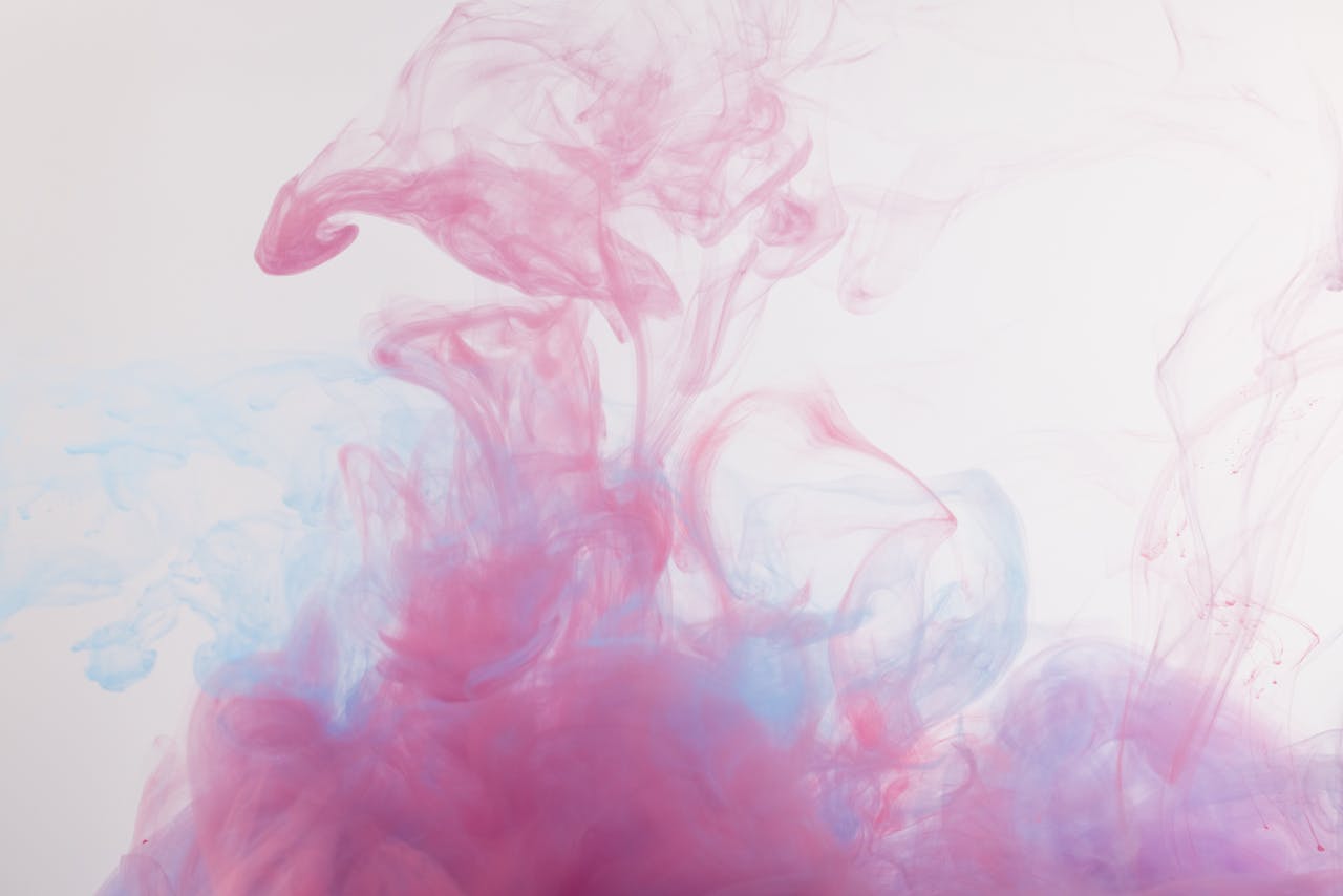 Vibrant and ethereal swirling patterns of pink and blue smoke against a white background.